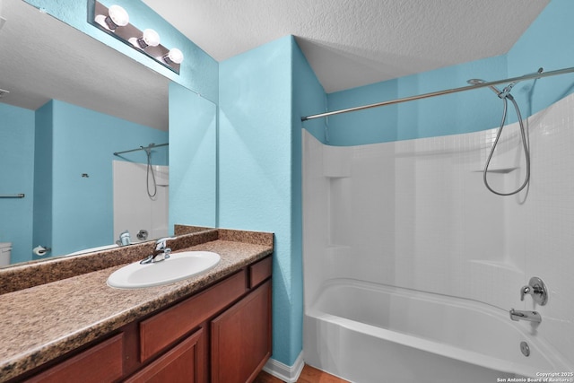 bathroom featuring bathtub / shower combination, a textured ceiling, and vanity