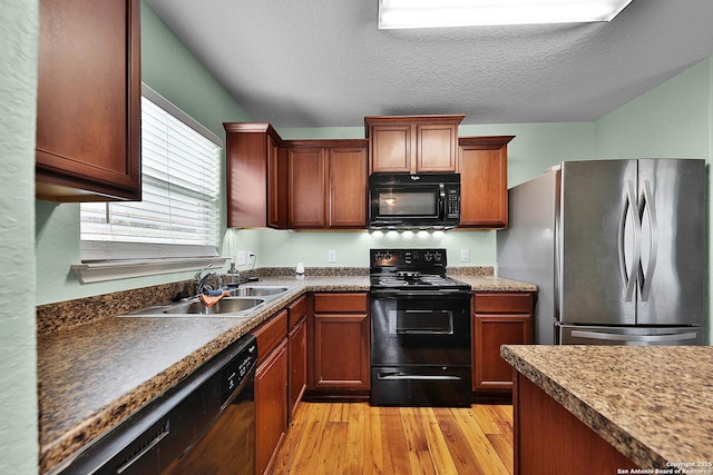 kitchen featuring a textured ceiling, sink, light hardwood / wood-style floors, and black appliances