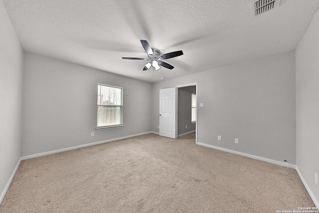 empty room with ceiling fan, light colored carpet, and a textured ceiling