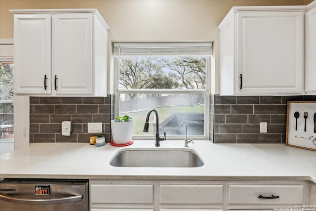 kitchen featuring stainless steel dishwasher, decorative backsplash, white cabinetry, and sink