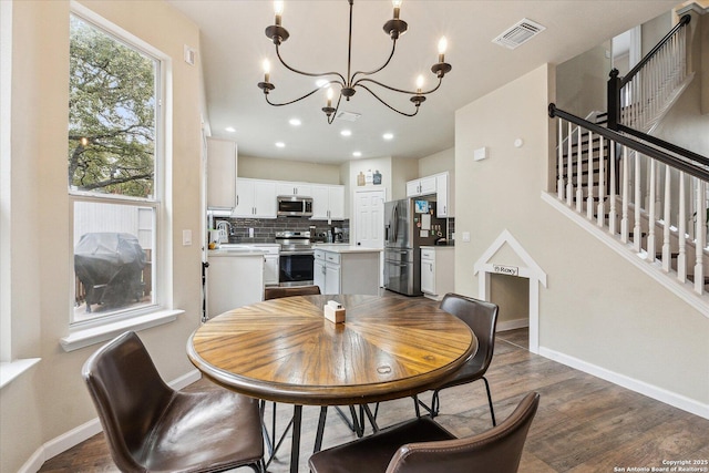 dining space featuring an inviting chandelier, sink, and dark wood-type flooring