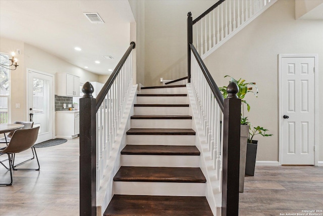 stairway featuring hardwood / wood-style floors and a notable chandelier