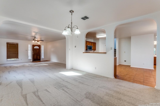 unfurnished living room with light carpet and ceiling fan with notable chandelier