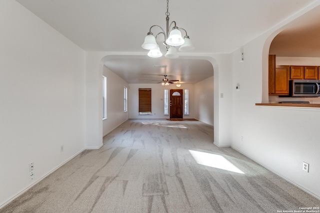 interior space with ceiling fan with notable chandelier and light colored carpet