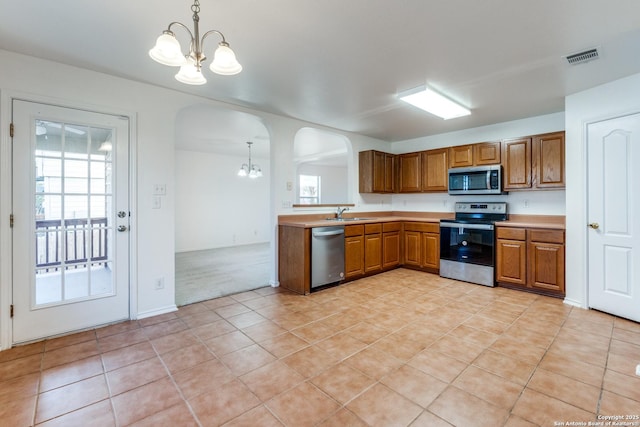 kitchen with stainless steel appliances, decorative light fixtures, and a notable chandelier