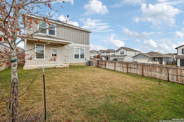 rear view of house with a lawn and central AC unit