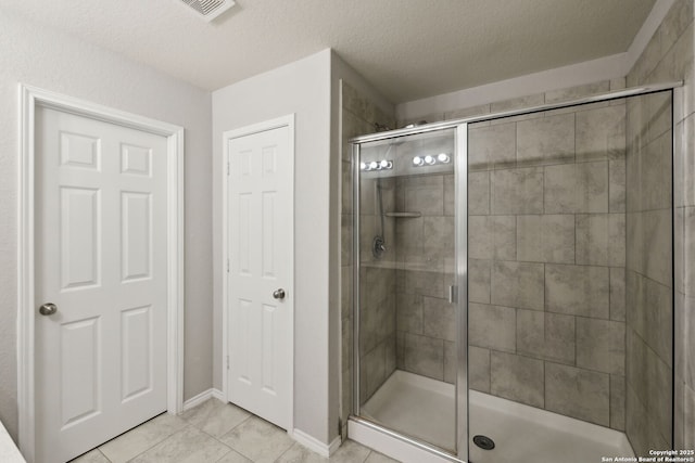 bathroom featuring tile patterned flooring, an enclosed shower, and a textured ceiling