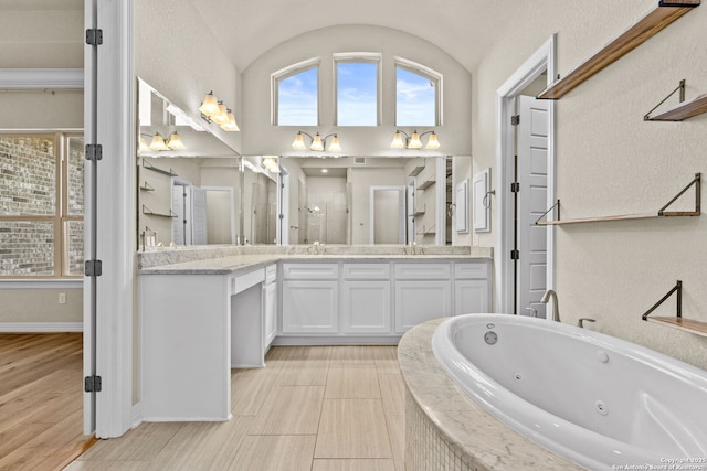 bathroom featuring vanity, tiled bath, and vaulted ceiling