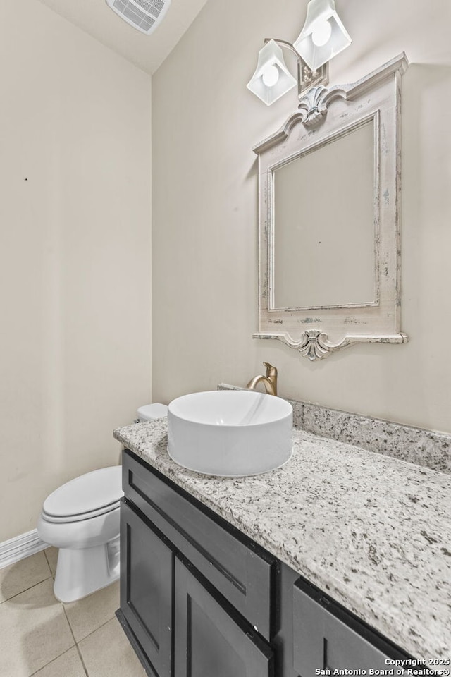 bathroom with toilet, vanity, and tile patterned floors