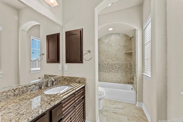 full bathroom featuring a wealth of natural light, vanity, toilet, and tiled shower / bath