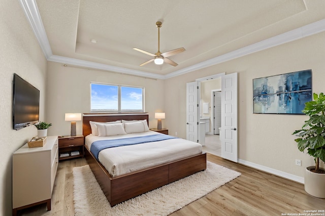 bedroom with ensuite bathroom, a raised ceiling, ceiling fan, ornamental molding, and light hardwood / wood-style floors