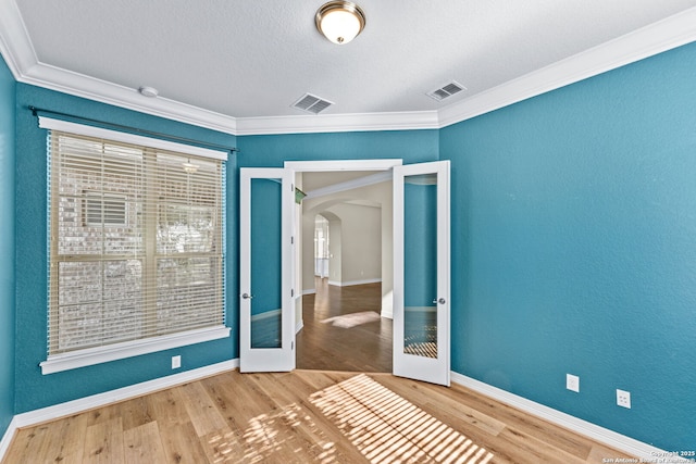 unfurnished bedroom featuring french doors, wood-type flooring, and ornamental molding