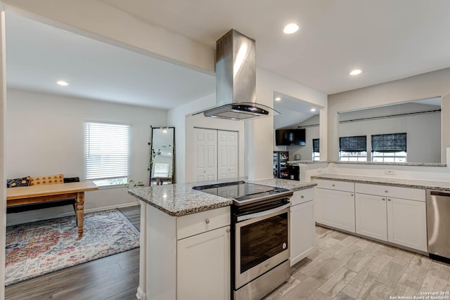 kitchen with a center island, white cabinets, light stone countertops, island range hood, and stainless steel appliances