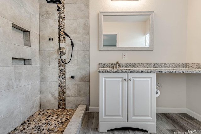 bathroom with hardwood / wood-style flooring, vanity, and tiled shower