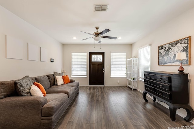 living room featuring plenty of natural light, ceiling fan, and dark wood-type flooring