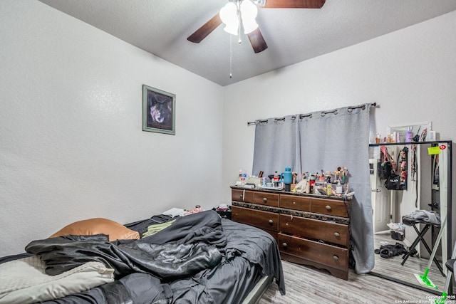 bedroom featuring ceiling fan, light hardwood / wood-style floors, and a textured ceiling