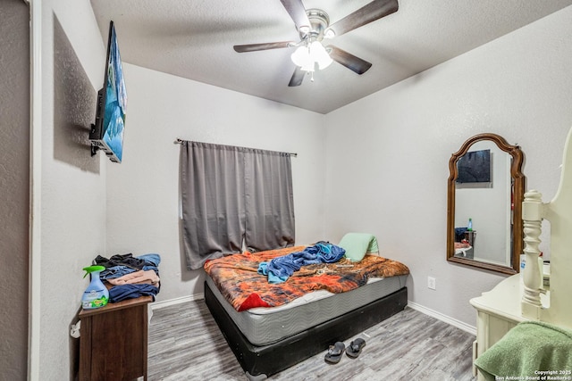 bedroom with a textured ceiling, hardwood / wood-style flooring, and ceiling fan