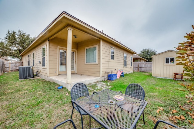 rear view of property featuring a lawn, a patio area, a storage shed, and central AC