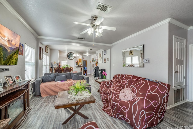 living room with hardwood / wood-style floors, ceiling fan with notable chandelier, crown molding, and a textured ceiling