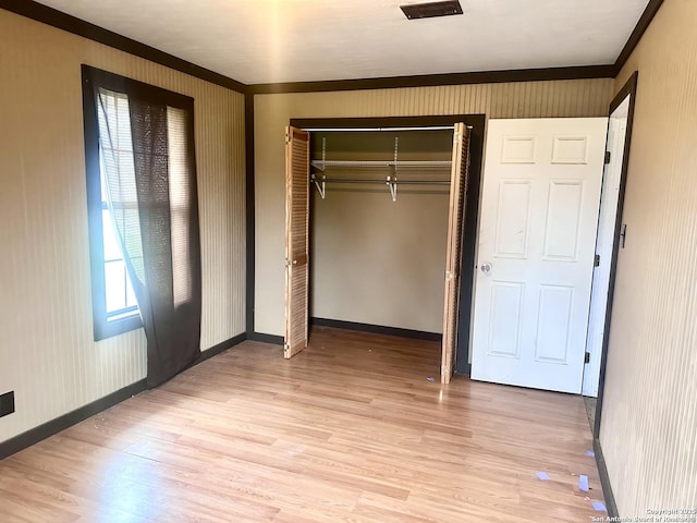 unfurnished bedroom featuring a closet, light hardwood / wood-style flooring, and ornamental molding