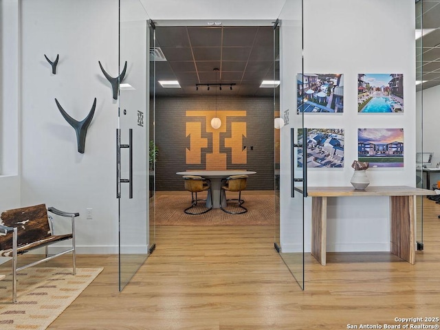 corridor with hardwood / wood-style floors and track lighting