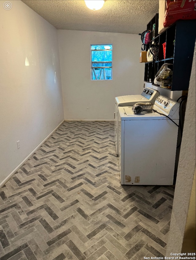 clothes washing area featuring a textured ceiling and washer and clothes dryer