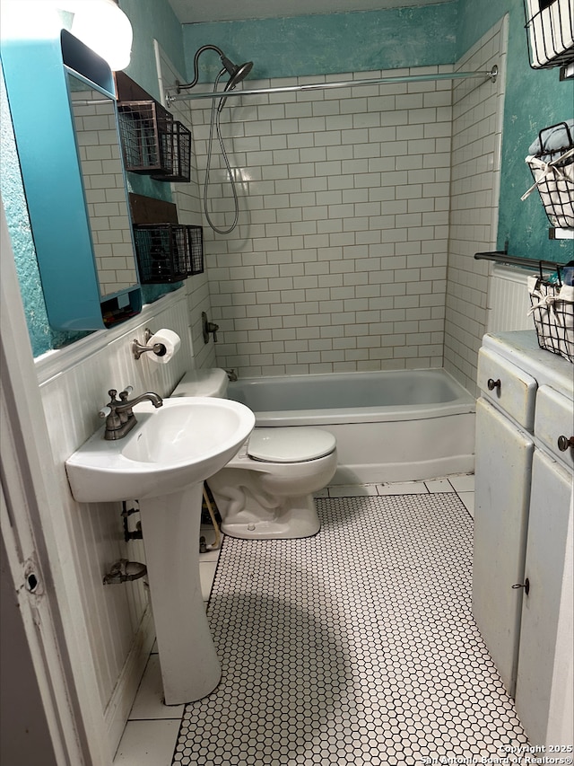 bathroom with tile patterned floors, tiled shower / bath combo, and toilet