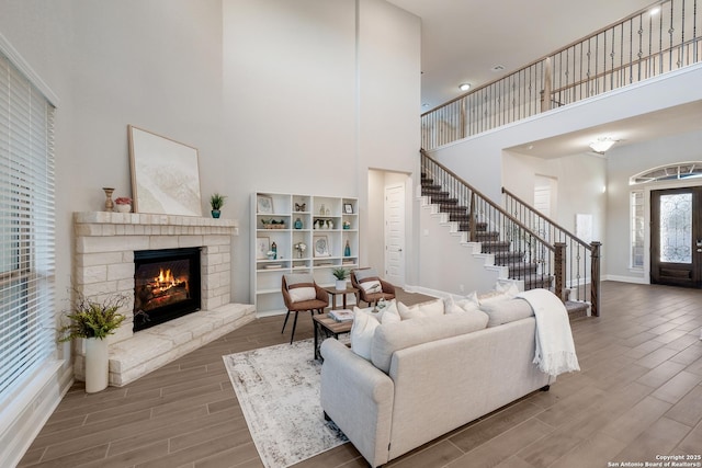 living room featuring a stone fireplace, a towering ceiling, and french doors