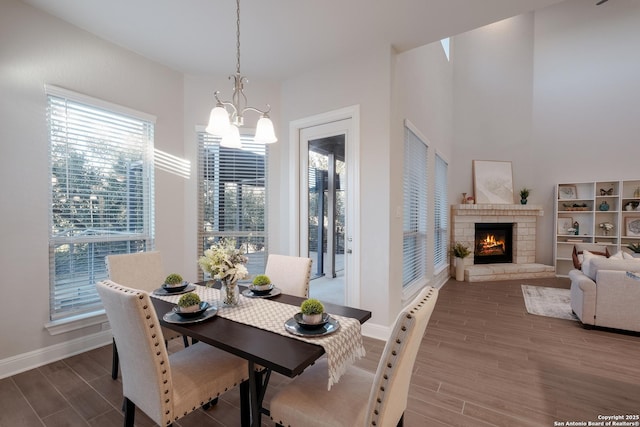 dining area featuring a notable chandelier and a stone fireplace