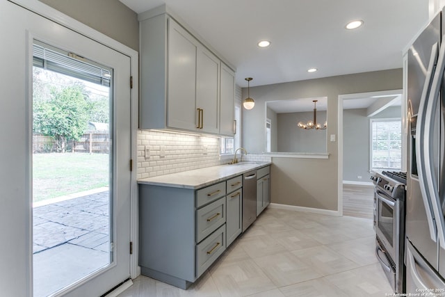 kitchen featuring decorative backsplash, stainless steel appliances, an inviting chandelier, and a wealth of natural light