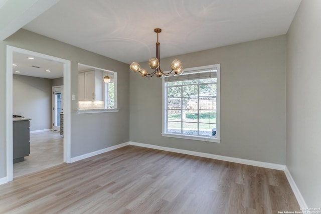 spare room featuring light wood-type flooring and an inviting chandelier