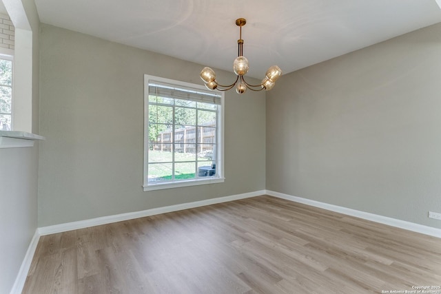 empty room featuring light hardwood / wood-style flooring and a notable chandelier