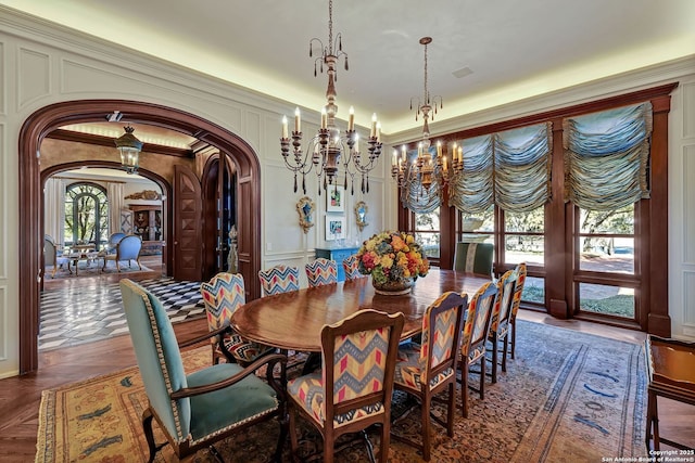 dining area featuring arched walkways, a decorative wall, and ornamental molding