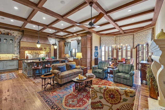 living area featuring light wood finished floors, coffered ceiling, ceiling fan with notable chandelier, beam ceiling, and recessed lighting