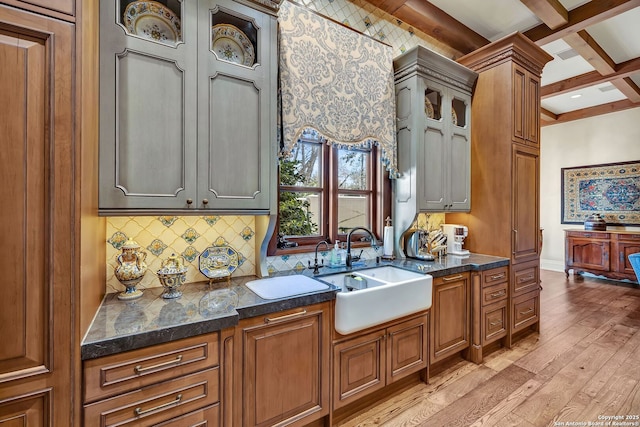 kitchen with decorative backsplash, coffered ceiling, beamed ceiling, light wood-style floors, and a sink