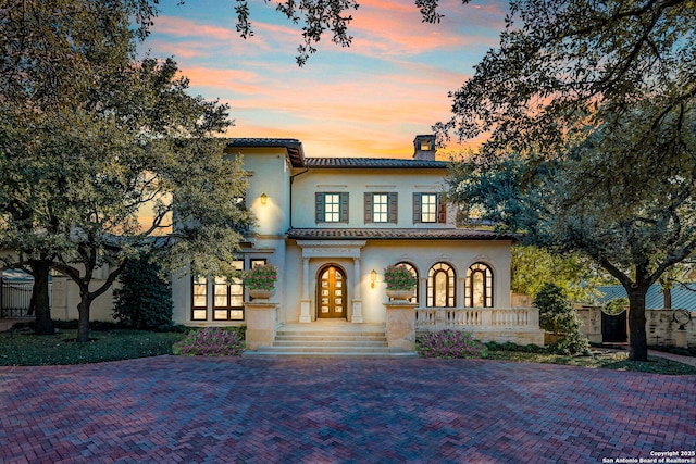 mediterranean / spanish-style home with french doors, fence, a chimney, and stucco siding