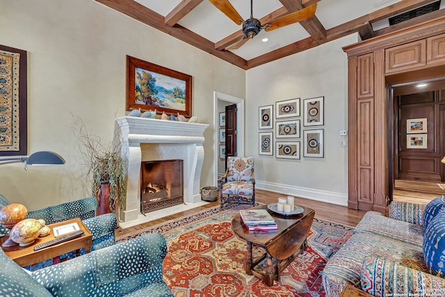 living room featuring baseboards, coffered ceiling, a ceiling fan, wood finished floors, and a fireplace