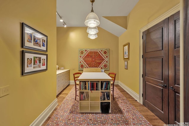 dining area featuring track lighting, light wood-type flooring, and baseboards