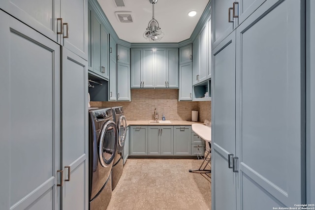 clothes washing area with cabinet space, visible vents, a chandelier, separate washer and dryer, and a sink