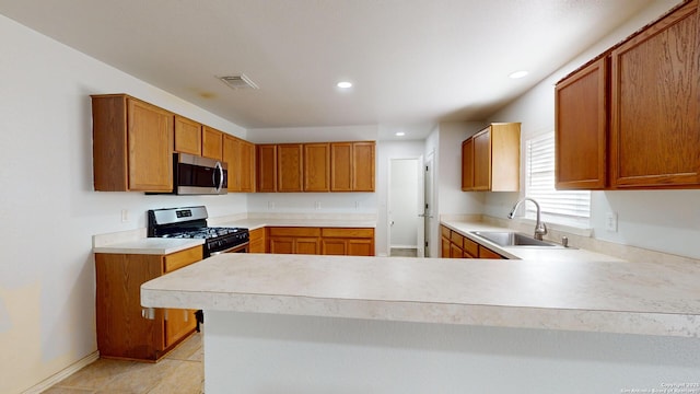 kitchen featuring light tile patterned floors, kitchen peninsula, sink, and appliances with stainless steel finishes