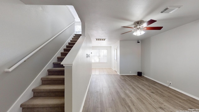 stairway with ceiling fan and hardwood / wood-style flooring