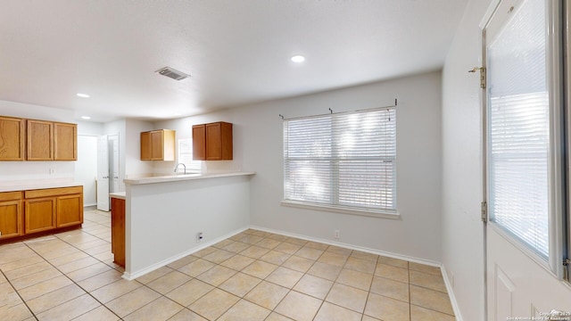 kitchen featuring kitchen peninsula, light tile patterned floors, and a wealth of natural light