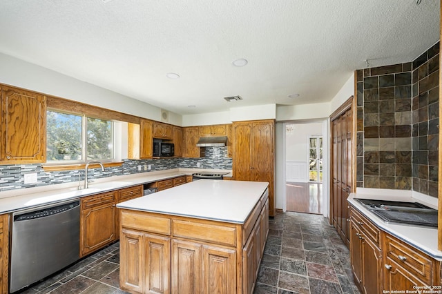 kitchen with appliances with stainless steel finishes, backsplash, a textured ceiling, sink, and a kitchen island