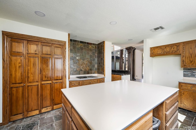 kitchen featuring a center island, a textured ceiling, gas cooktop, and tasteful backsplash