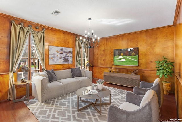 living room with wooden walls, light hardwood / wood-style flooring, and a notable chandelier