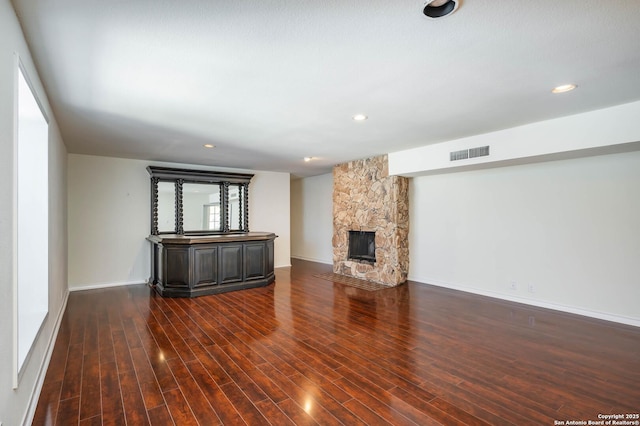 unfurnished living room featuring dark hardwood / wood-style flooring and a stone fireplace