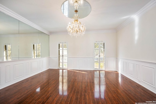 empty room featuring hardwood / wood-style flooring, an inviting chandelier, and crown molding