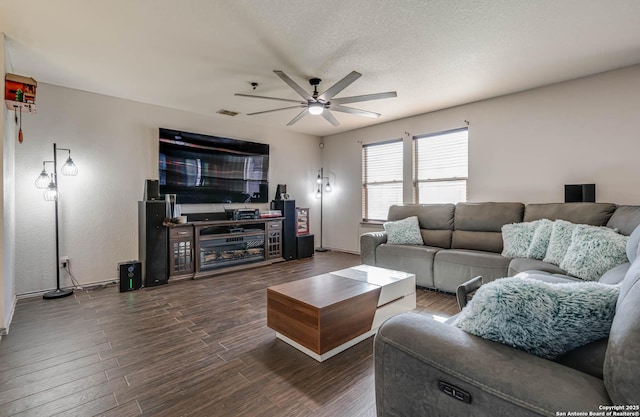 living room featuring a textured ceiling, ceiling fan, and dark wood-type flooring