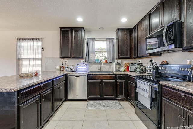 kitchen featuring sink, light tile patterned floors, a textured ceiling, kitchen peninsula, and stainless steel appliances