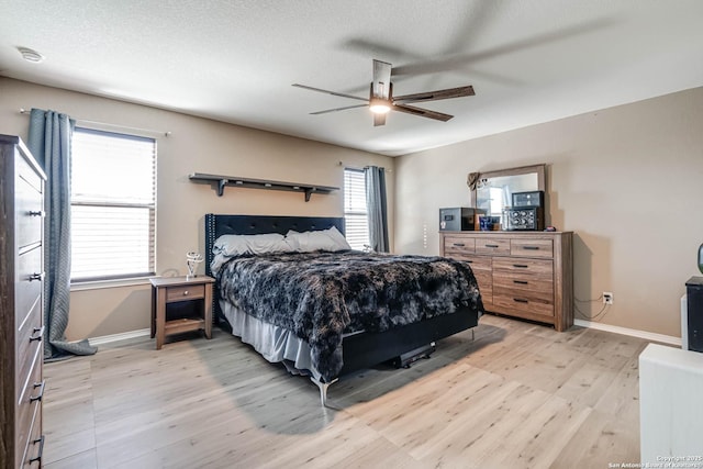 bedroom with a textured ceiling, light hardwood / wood-style floors, and ceiling fan